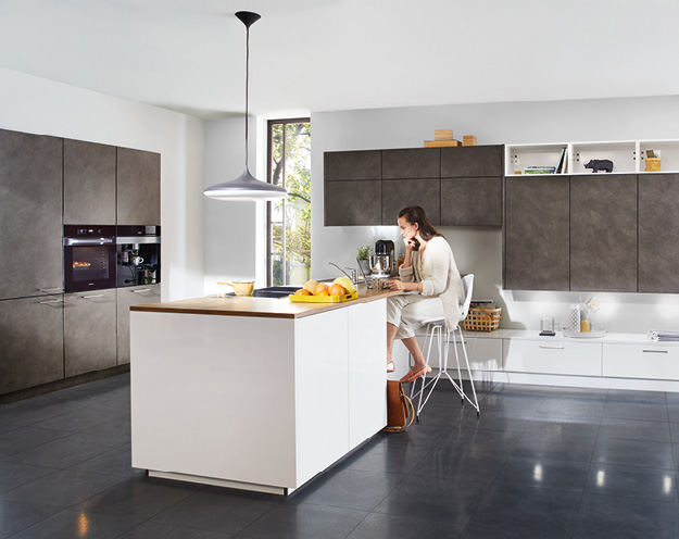 Frau auf Stuhl an Kücheninsel in moderner graubrauner Küche